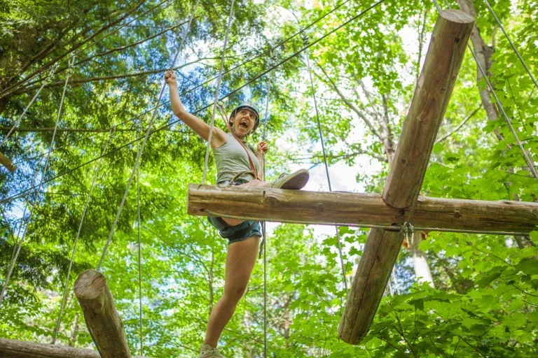 Une participante franchit un obstacle en hauteur dans un parcours Arbraska
