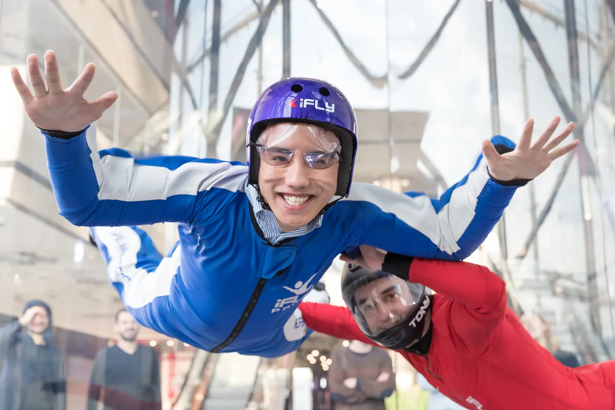 Un participant vole avec son instructeur dans la soufflerie intérieure iFLY