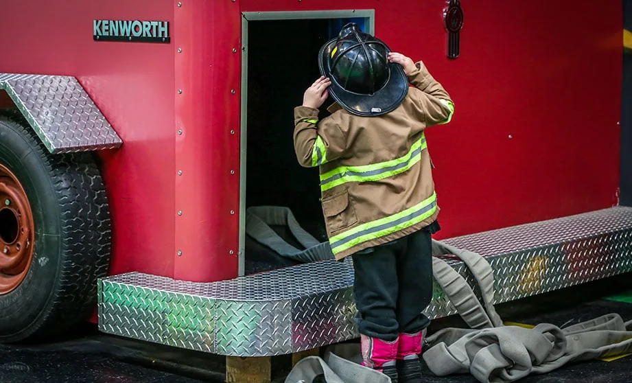 Enfant en costume de pompier montant dans le camion du musée