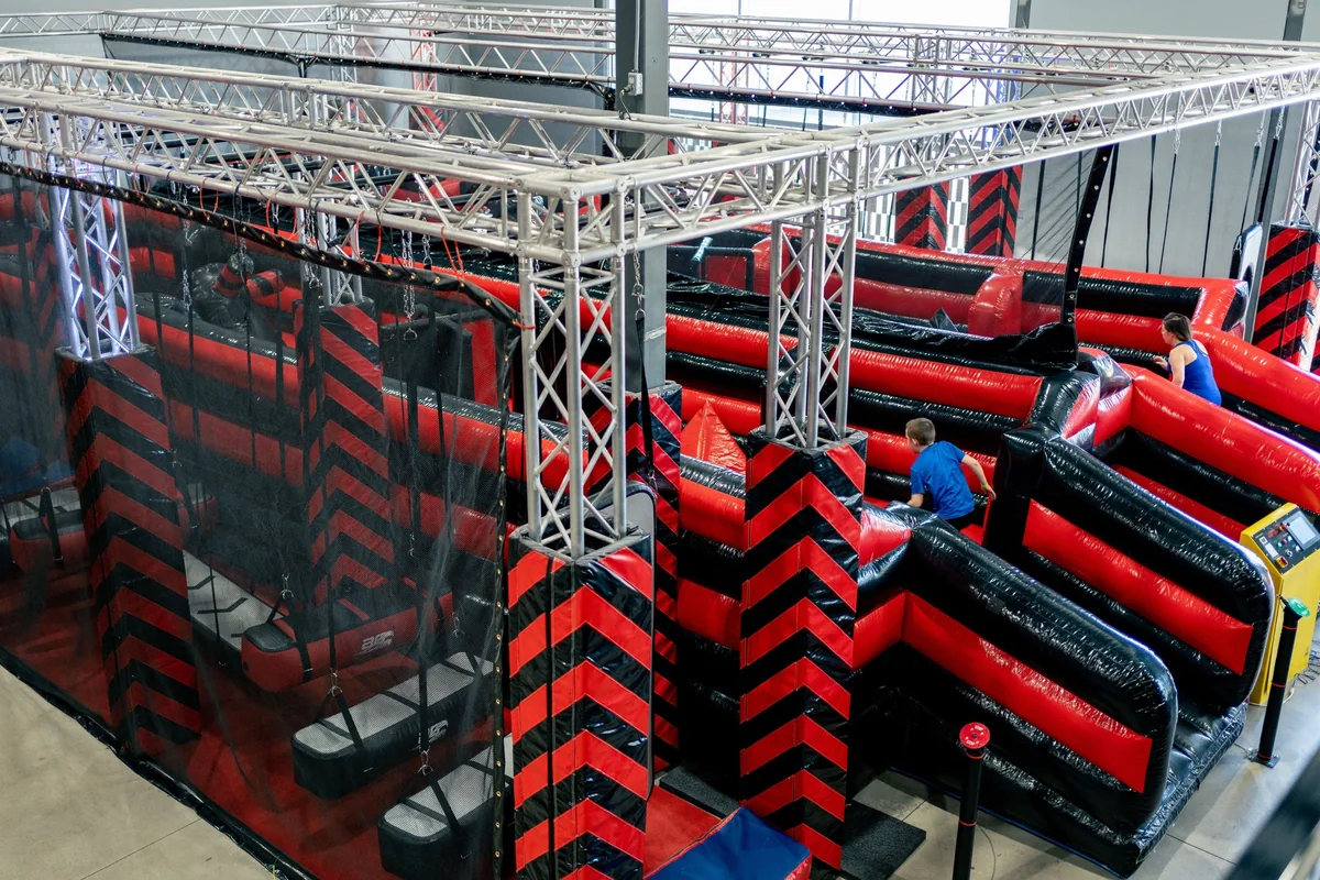Un enfant court dans le parcours gonflable rouge et noir de Ninja Factory