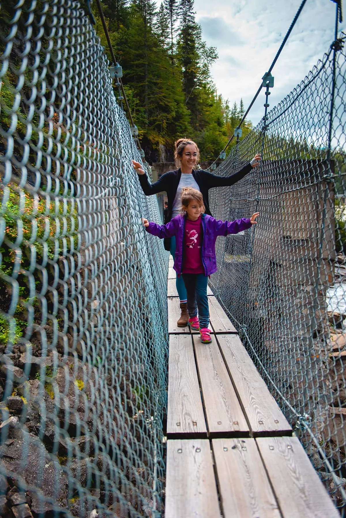 Adulte et enfant traversant un pont suspendu au-dessus du canyon