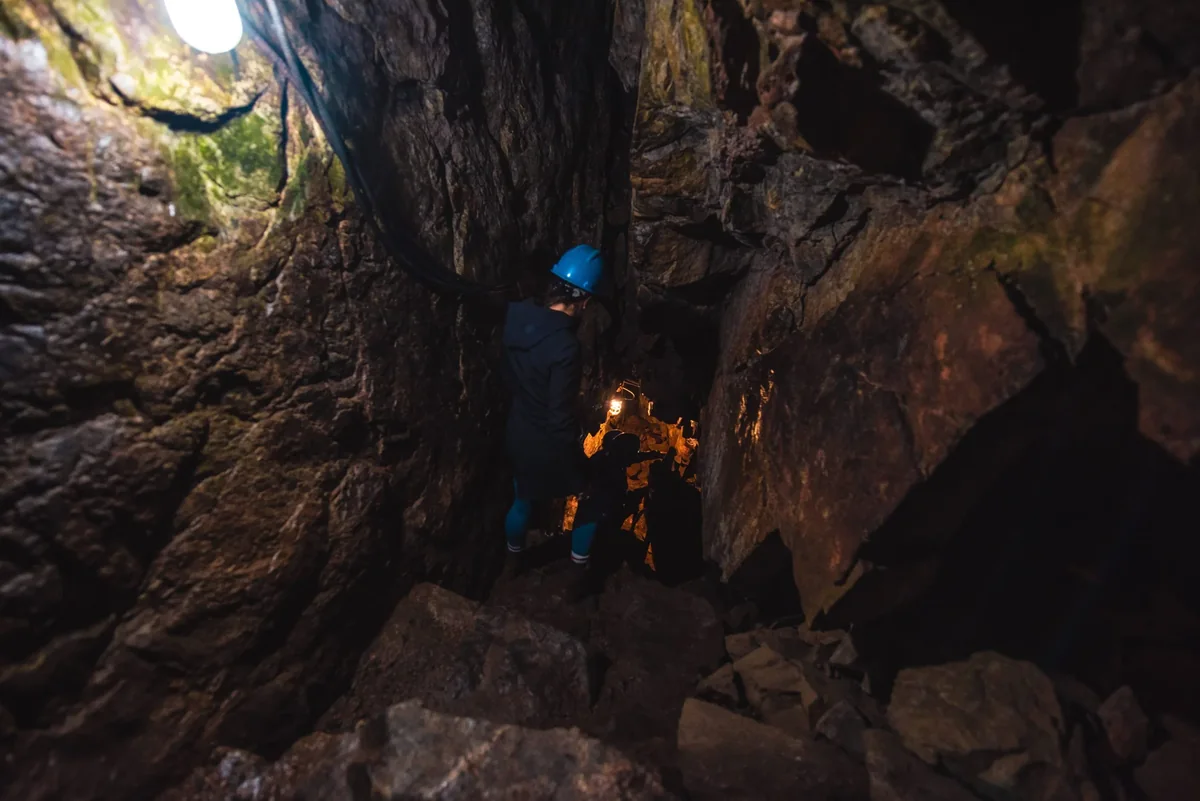 Visiteurs casqués descendant dans la caverne du Trou de la Fée