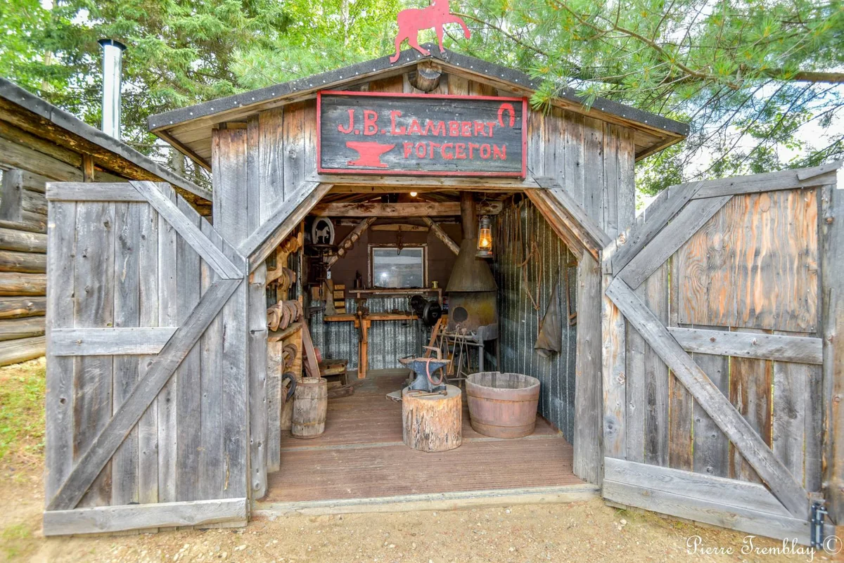 Forge et outils forestiers présentés dans un bâtiment en bois du Village du bûcheron